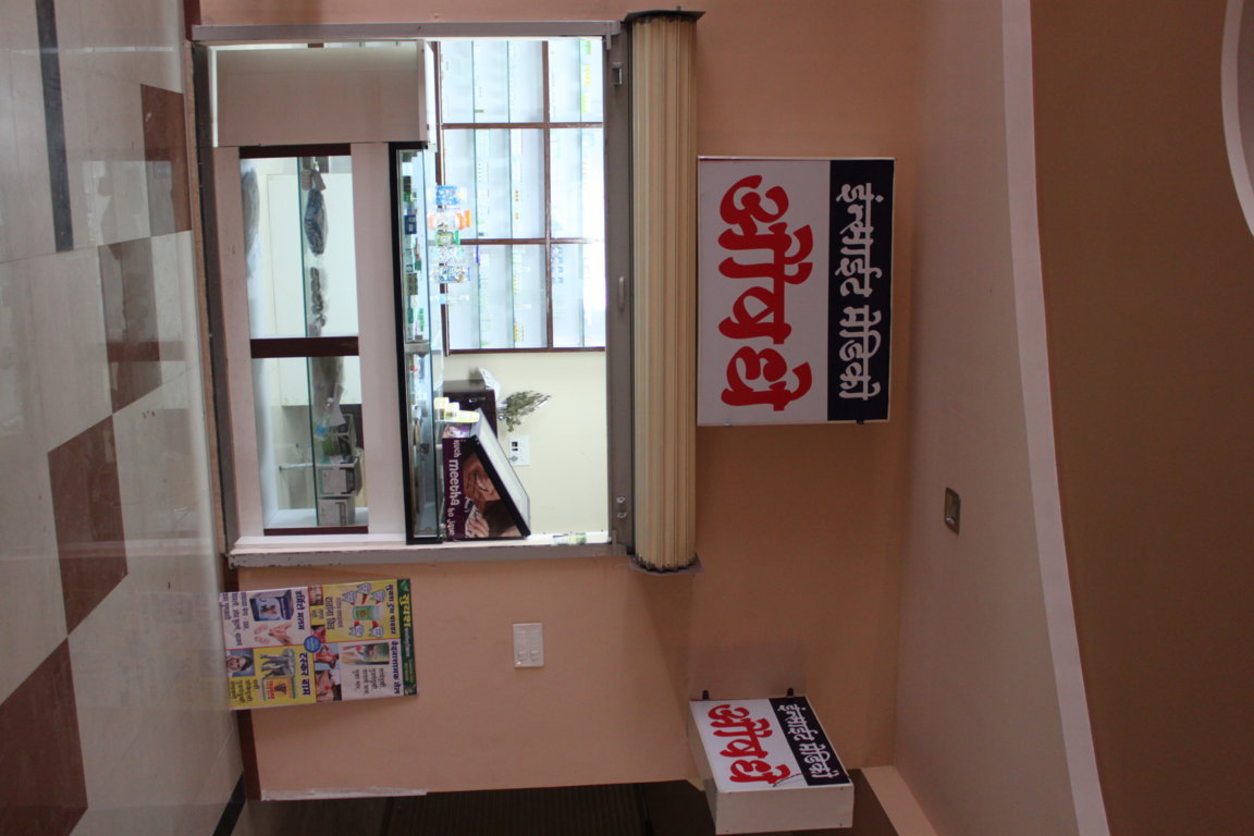 Insight Medico pharmacy service window at Insight Institute framed by the red Marathi 'Aushadhi' signboard and patient education posters